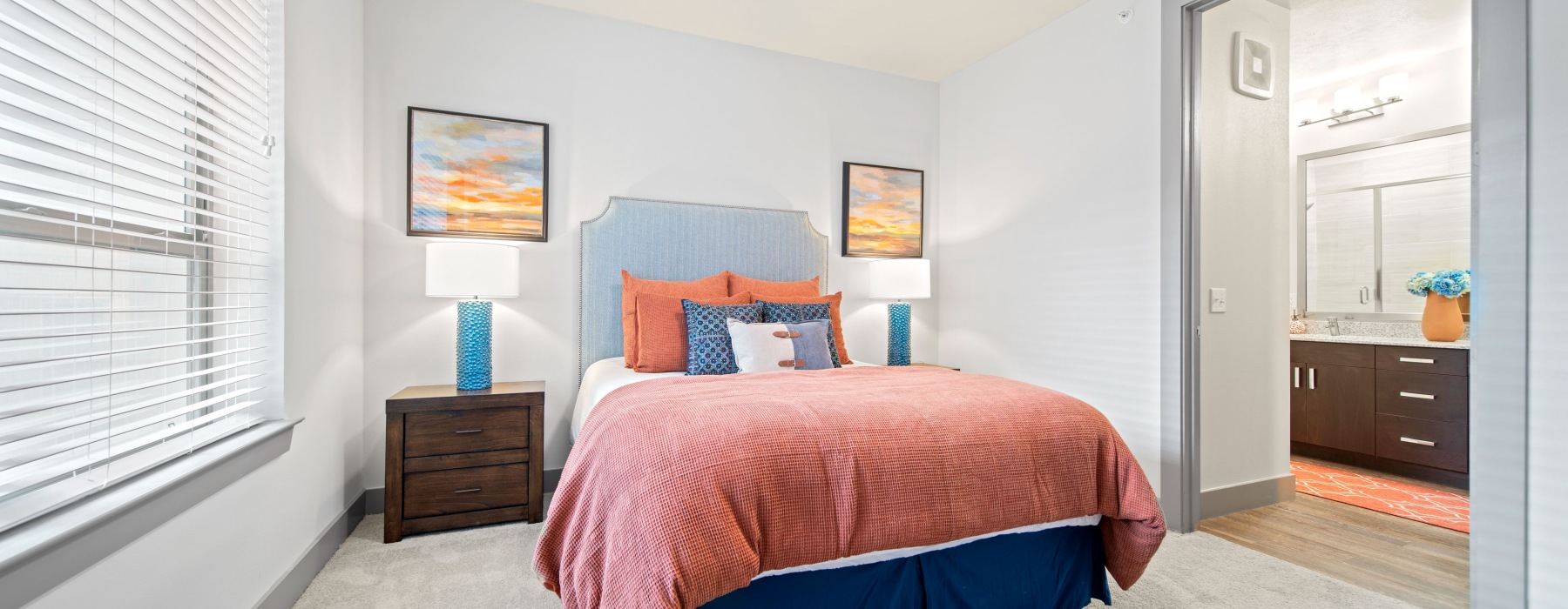 Bedroom with queen sized bed, two night stands, and a large window overlooking courtyard